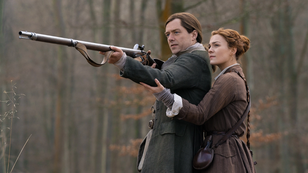 Brianna (Sophie Skelton) ensina Roger (Richard Rankin) a atirar em cena de Outlander.
