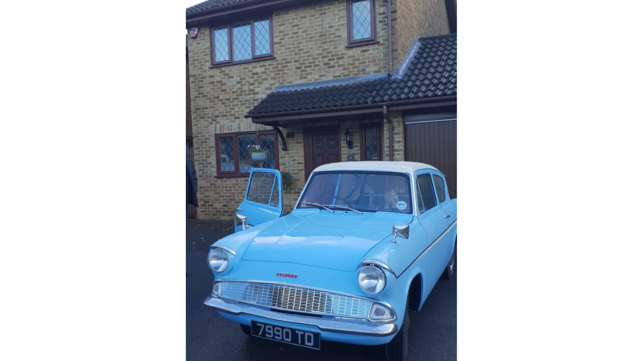 Ford Anglia azul estacionado na frente da casa onde a franquia Harry Potter foi gravada, com uma coruja dentro.
